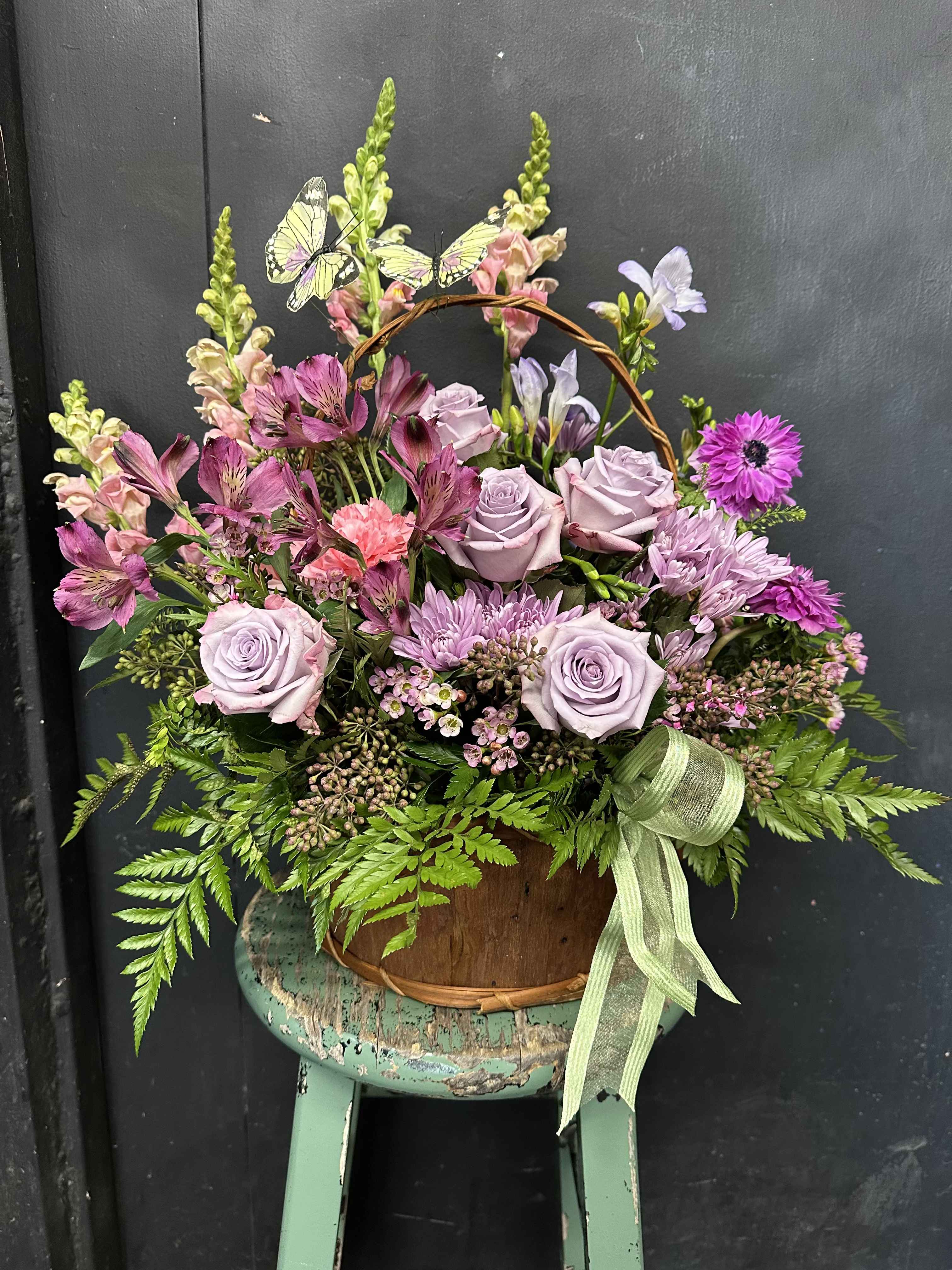 Basket arrangement of lavender roses and pink flowers with butterflies