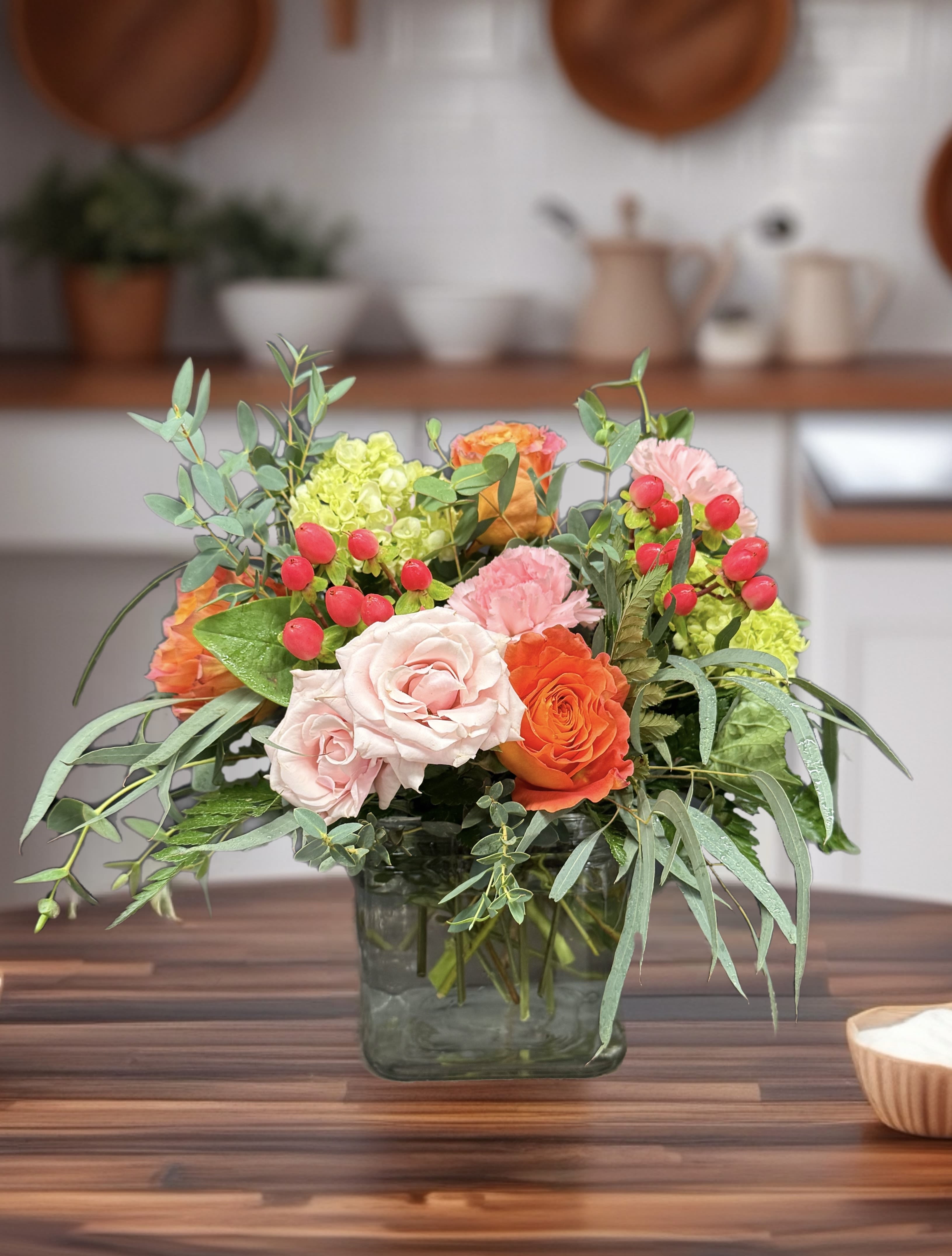 Mixed bouquet of pink and orange roses in a square glass vase