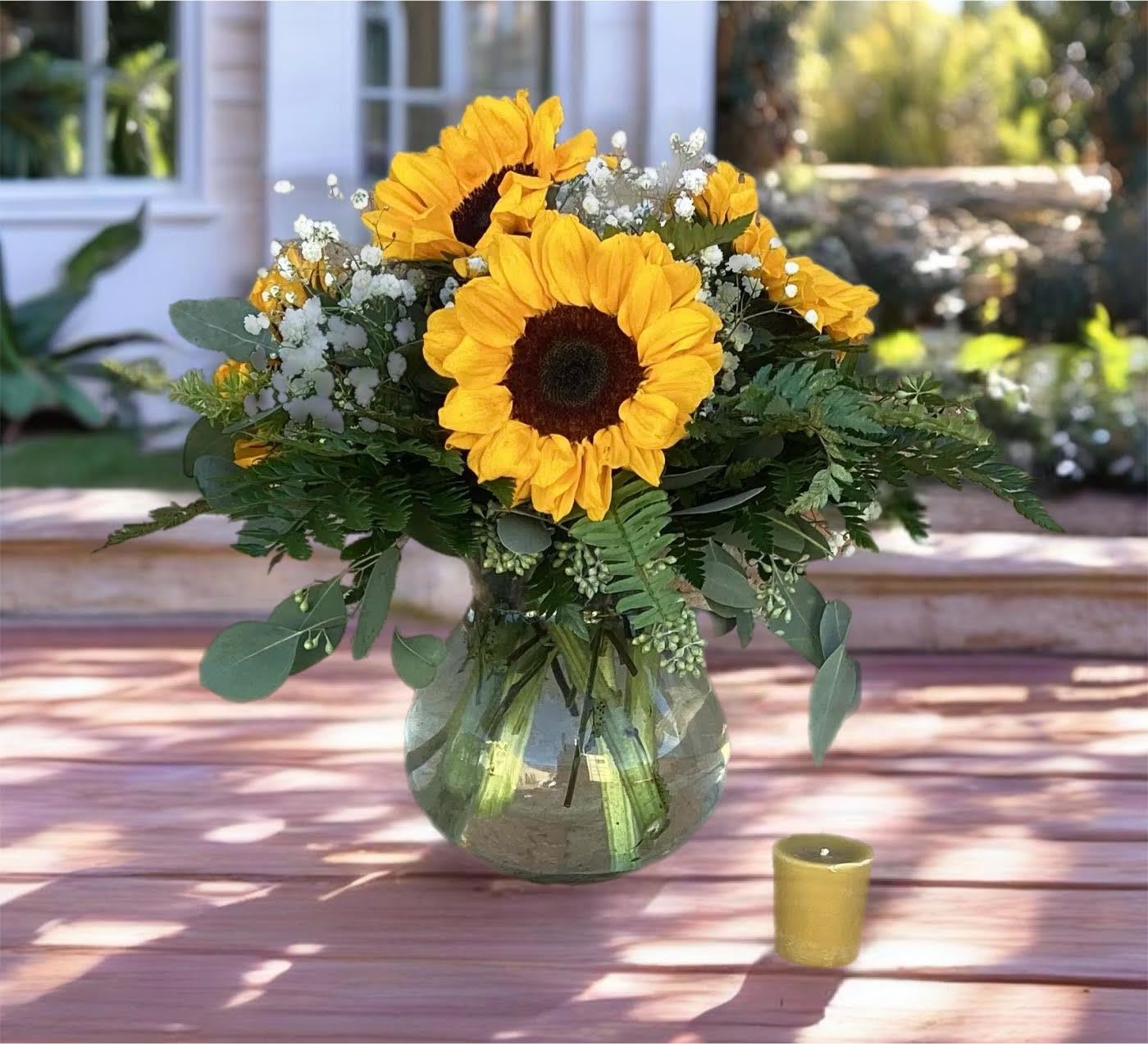 Sunflower bouquet in a glass vase with a small candle nearby