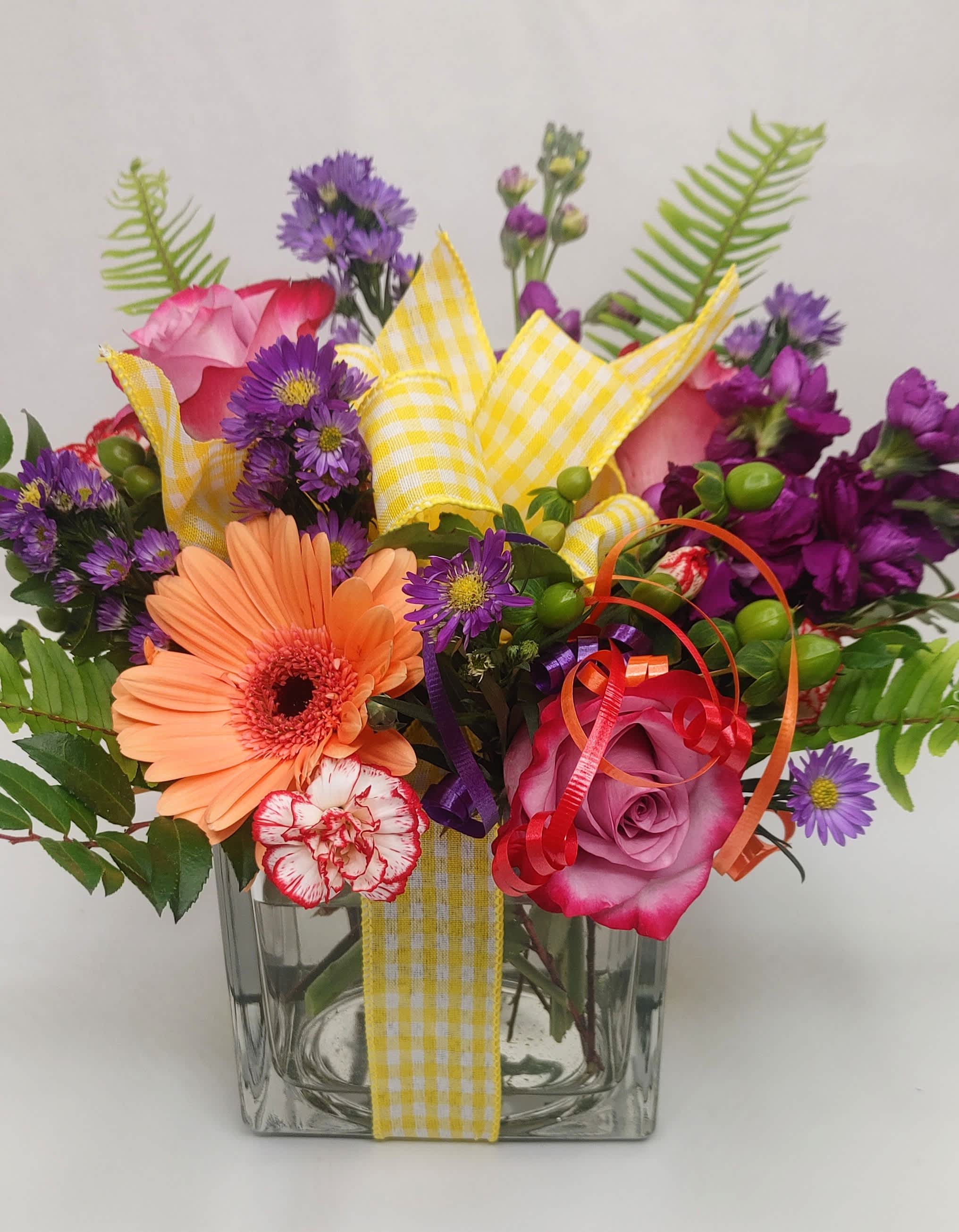 Mixed bouquet in a clear glass vase with pink, purple, and peach flowers