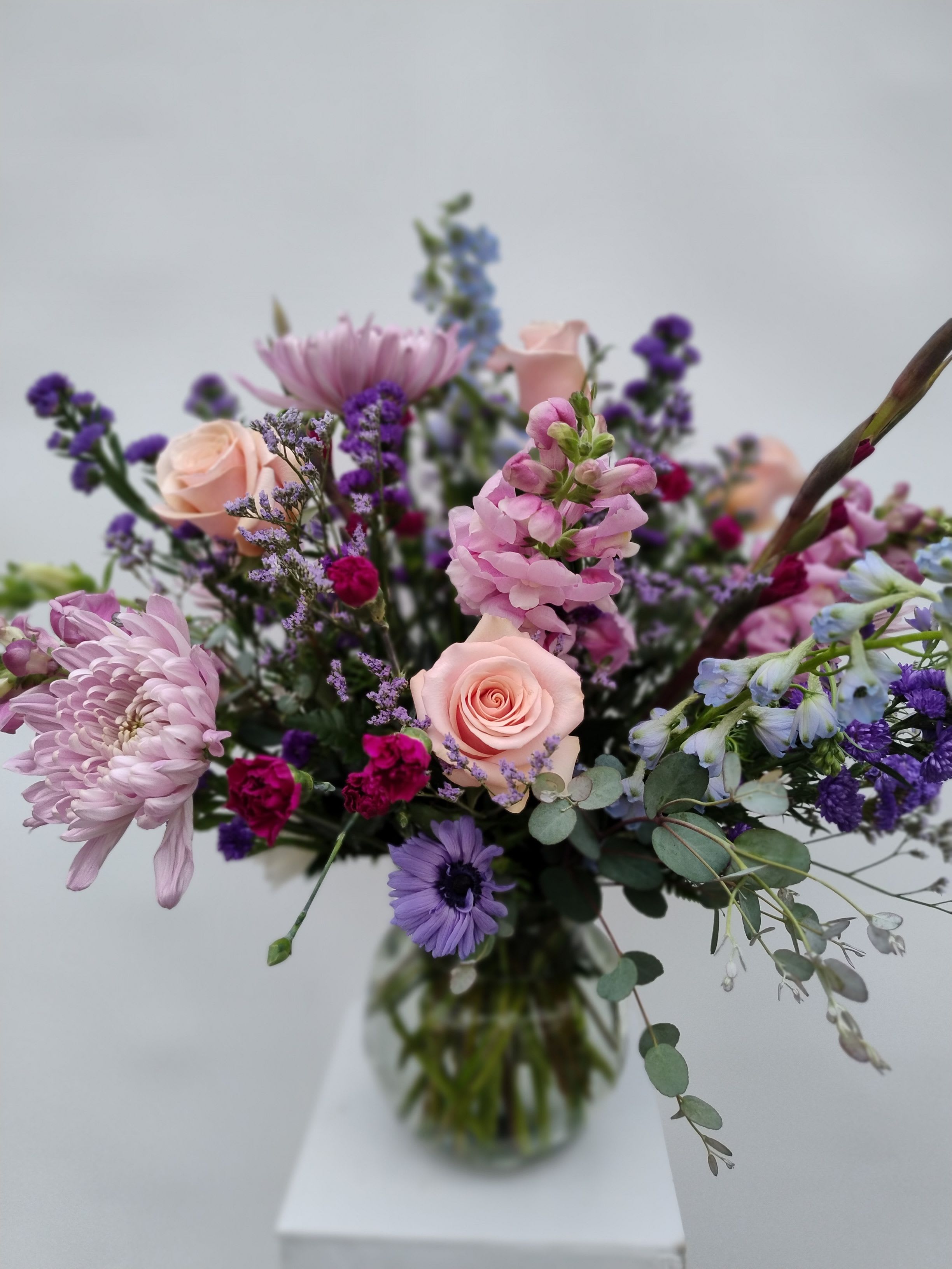 Mixed bouquet of pink and purple flowers in a glass vase