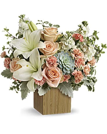 Arrangement of white lilies, peach roses, and carnations in a wooden cube vase