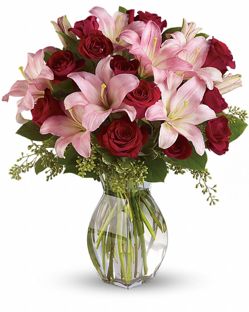 Bouquet of pink lilies and red roses in a clear glass vase