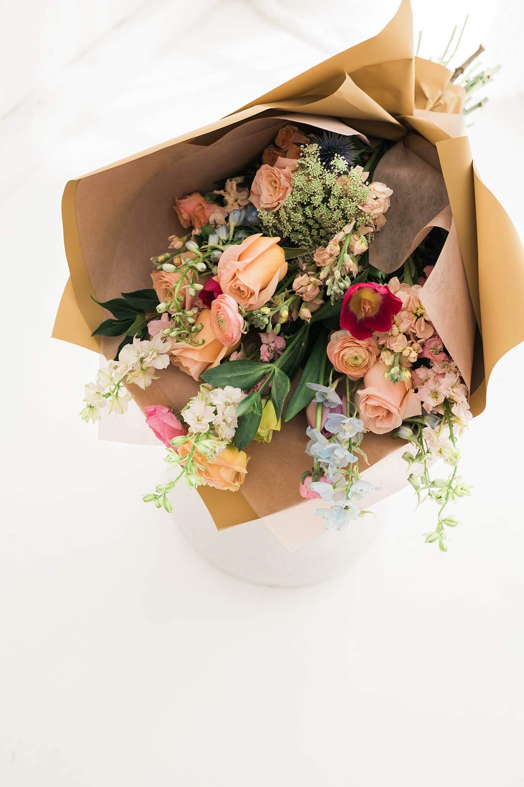 Wrapped bouquet of peach and pink flowers with mixed blooms