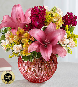 The FTD Pink Poise Bouquet - Beautifully composed of harmonizing shades of pink ranging from peach to coral to magenta and highlighted with a happy splash of yellow, it includes roses, LA Hybrid and Peruvian Lilies, mini-carnations, stock and more.
