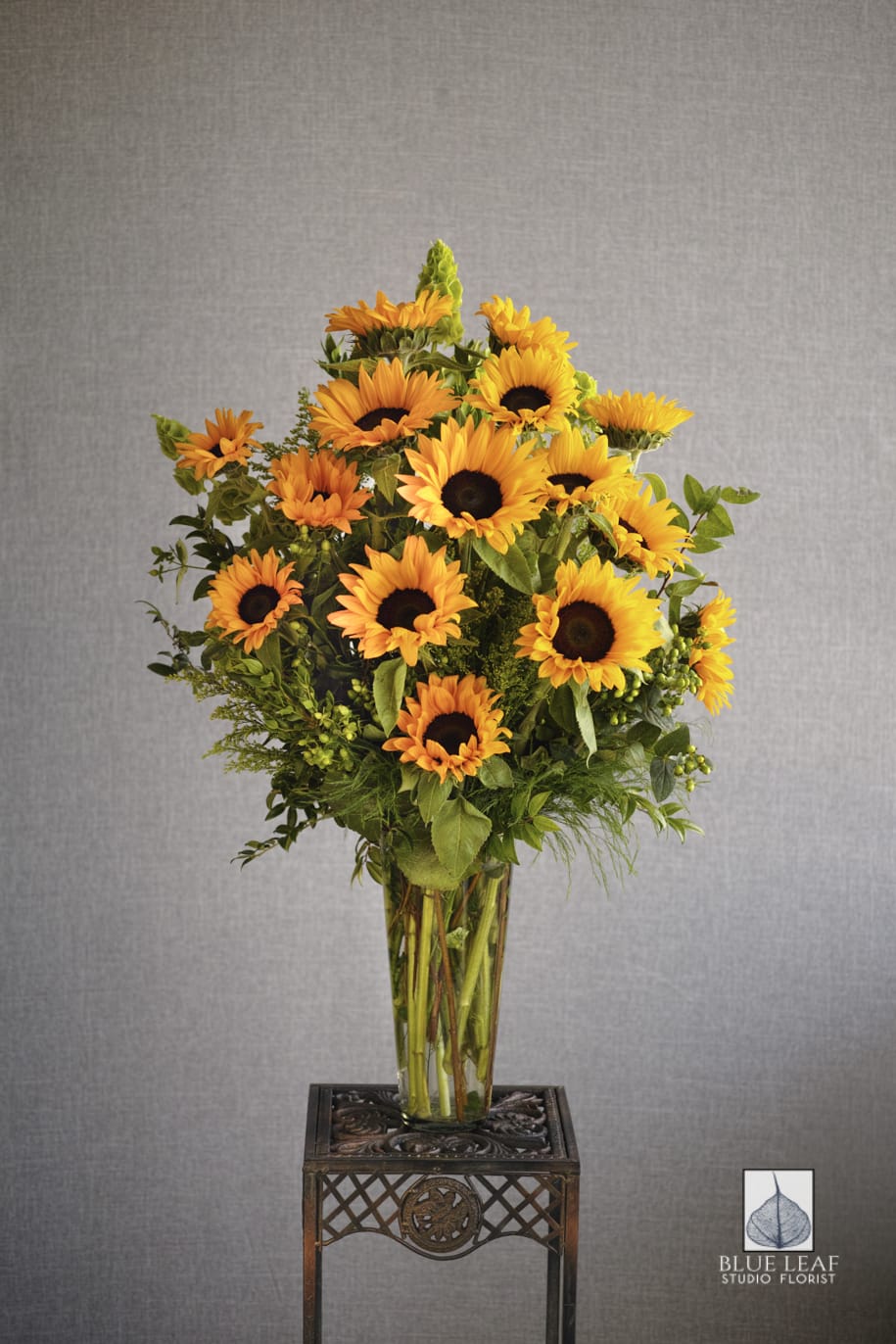 Spectacular Sunflowers - A showy display of sunflowers and a mix of greenery in a tall vase.