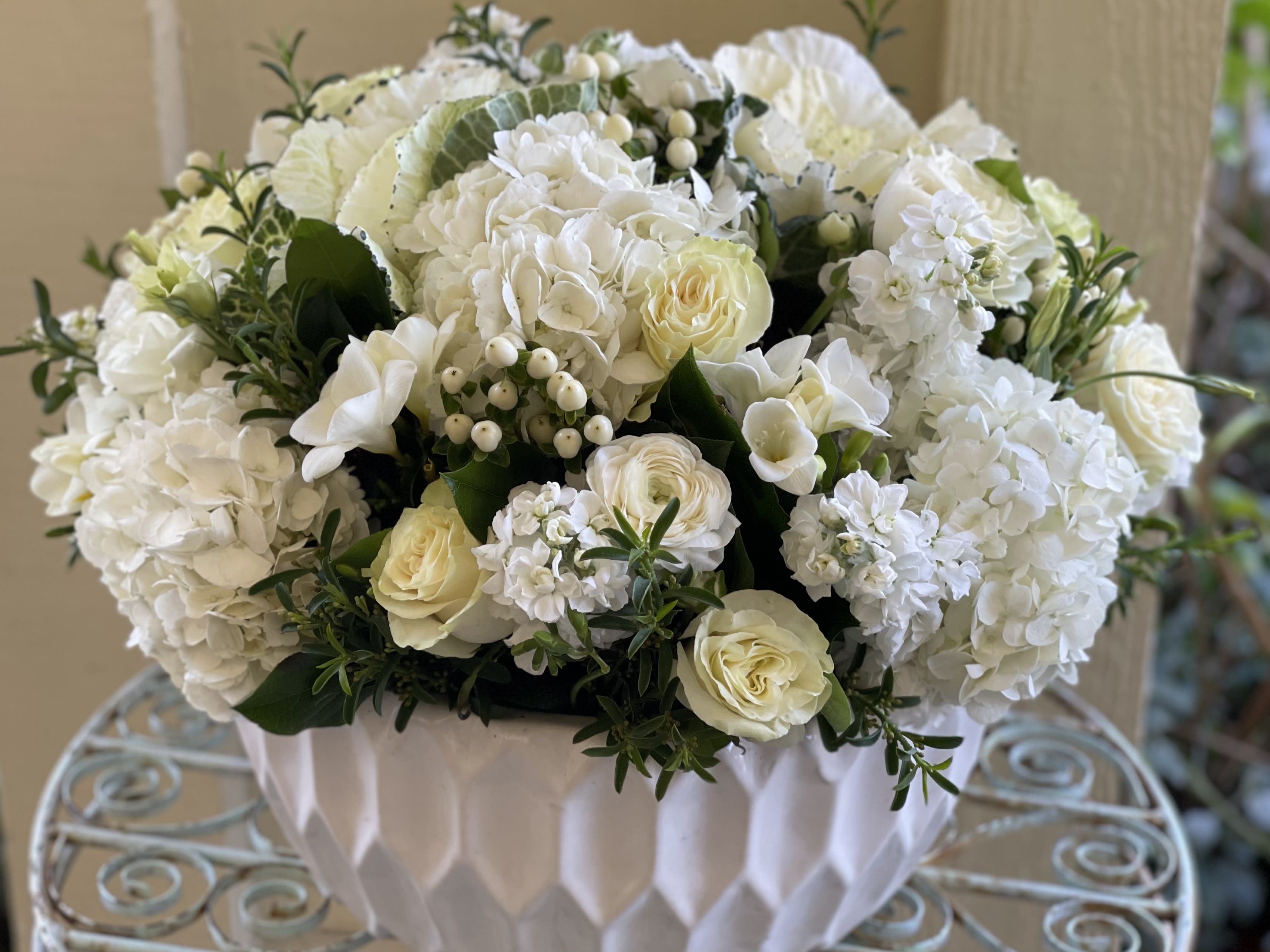 Low white and ivory flower arrangement in a textured white bowl