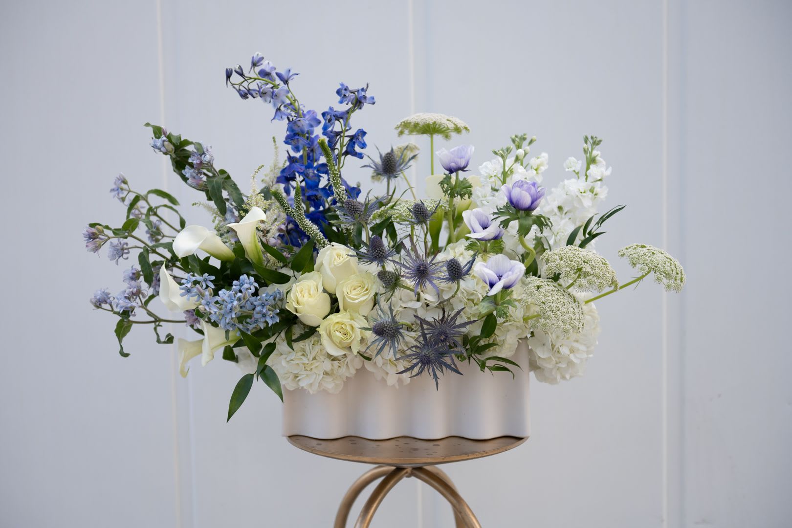 Blue, white, and cream floral arrangement in a white container