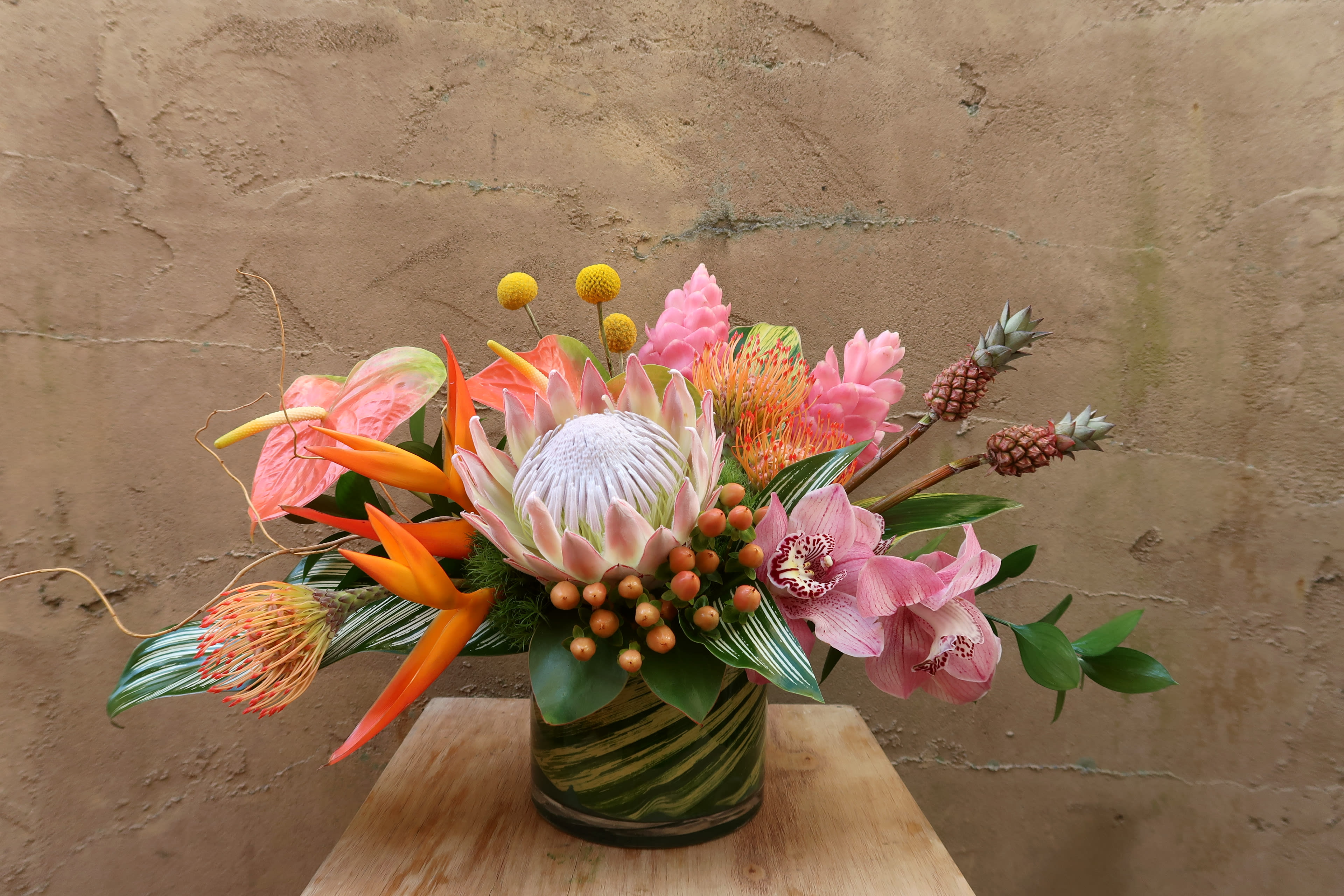 Tropical flower arrangement in a green glass vase with pink and orange blooms