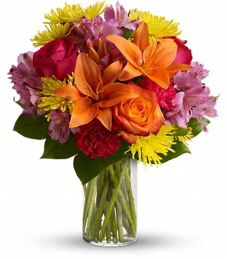 Colorful bouquet of lilies, roses, and daisies in a clear glass vase