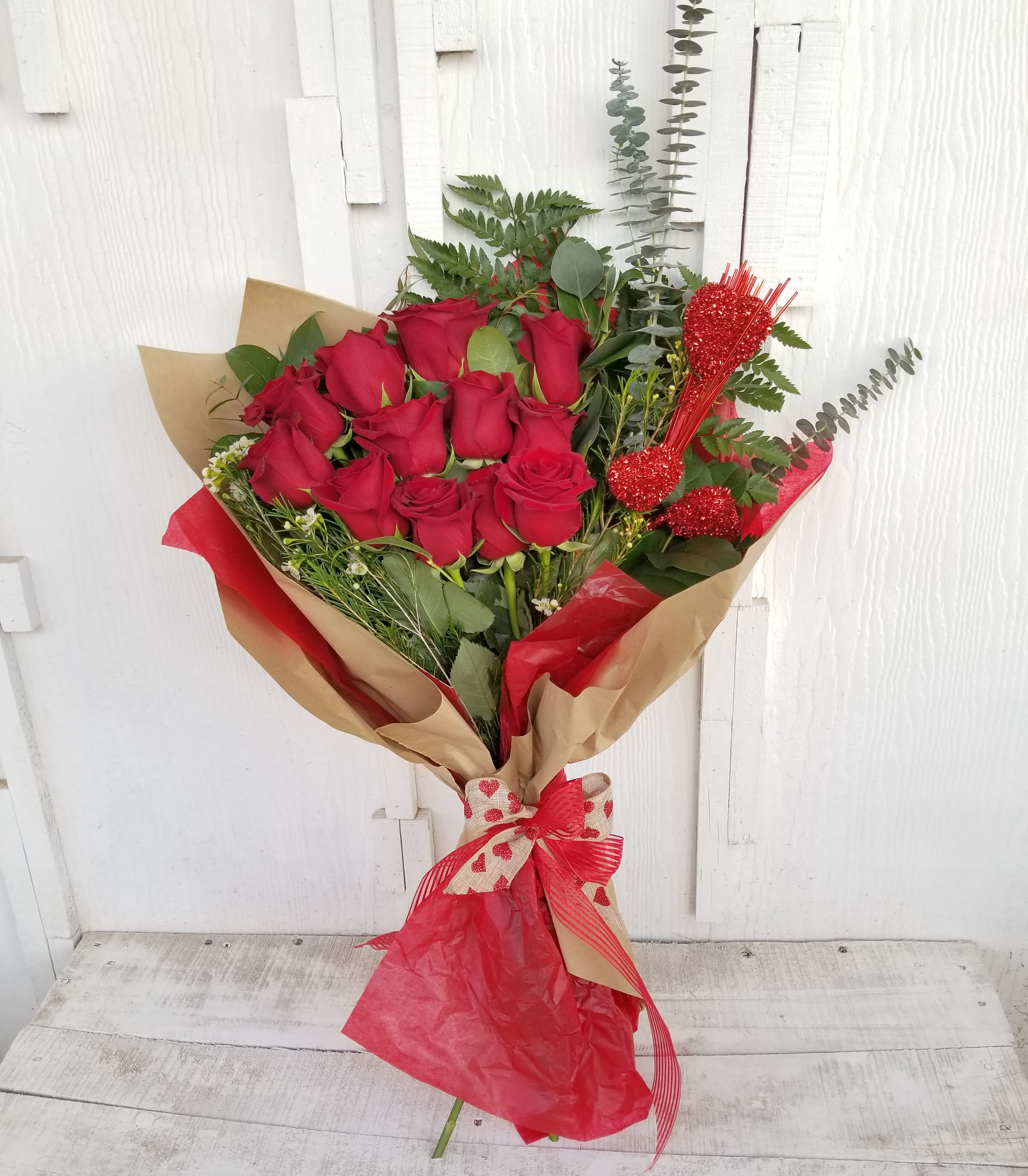 Bouquet of red roses wrapped in brown and red paper with a ribbon