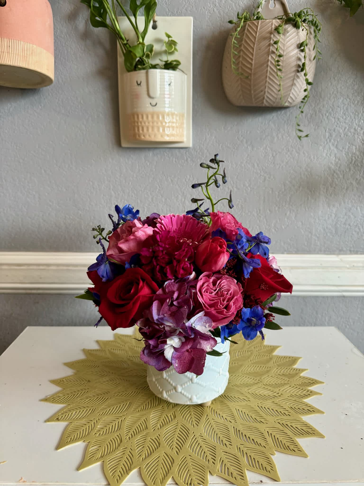Colorful bouquet of roses, hydrangea, and blue flowers in a white vase