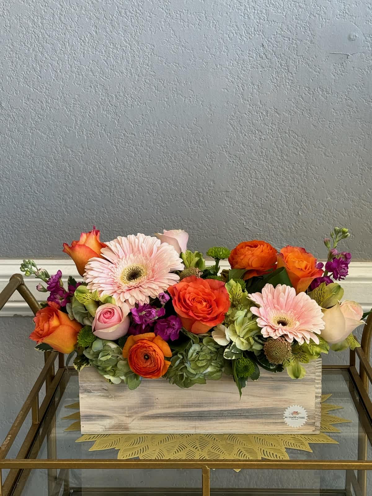 Mixed bouquet of orange, pink, and purple flowers in a wooden box