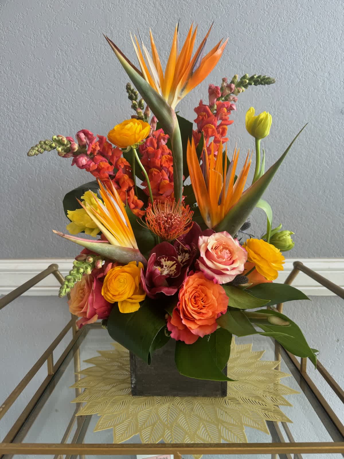 Medina - Tropical plants come together in this one-sided tall standing arrangement. Featuring birds of paradise and pincushion protea, this tropical selection would look lovely in any home. 