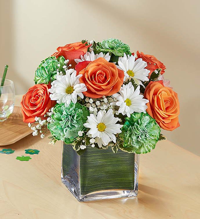 Orange roses and white daisies in a square glass vase