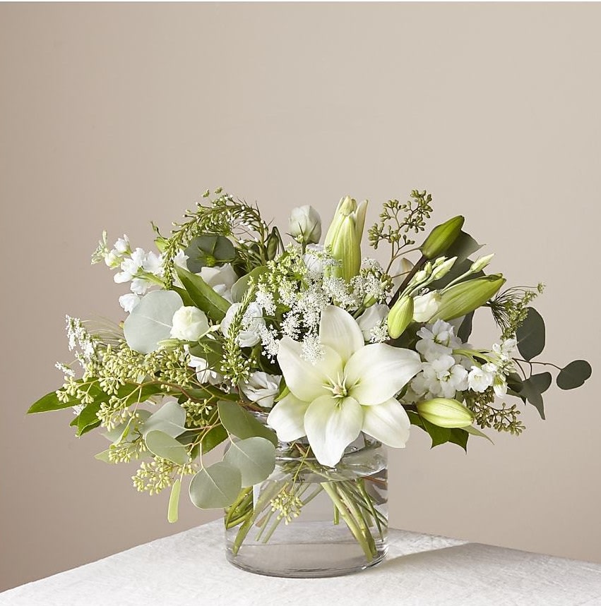 Alluring Elegance Bouquet - An illuminating array of florals brings an air of elegance to any room it's placed. This arrangement features refined florals like lilies, Queen Anne's Lace and Veronica in a clear glass vase to add a touch of sophisticated style to your special occasions.  Please Note: The bouquet pictured reflects our original design for this product. While we always try to follow the color palette, we may replace stems to deliver the freshest bouquet possible, and we may sometimes need to use a different vase.  DETAILS The Deluxe Bouquet is approximately 15"H x 17"W. The Premium Bouquet is approximately 20"H x 19"W. Designed by florists, ready to display. For long–lasting blooms, replace the water daily. We suggest trimming the stems every couple days. Pet Safety Precautions: This bouquet or plant may include flowers and foliage that are known to be toxic to pets. To keep them safe, be sure to keep this arrangement out of your pet's reach. STEMS Eucalyptus Lily Queen Anne's Lace Stock Veronica