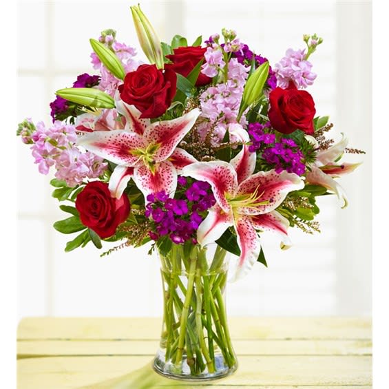 Elegant Beauty - Surprise someone you love with our beautifully hand-designed arrangement of roses, lilies, stock, dianthus and more. • Our florists select the freshest flowers available, so colors and varieties may vary due to local availability • Mixed bouquet of blooms, including roses, lilies, stock, dianthus, heather and variegated pittosporum • Lilies may arrive in bud form and will open to full beauty over the next 2-3 days • Artistically designeds in a clear glass vase