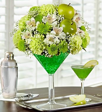 Apple Martini Bouquet - Stir up excitement with this original floral cocktail and make their friends green with envy. Inspired by the popular Appletini, our expert florists hand-arrange the freshest green carnations and poms with alstroemeria and fresh greenery, inside a keepsake acrylic martini glass. To complete the recipe, it's accented with green apple picks. Sure to make any hour Happy Hour.   Green and white arrangement of carnations, poms, alstroemeria, gypsophilia and variegated pittosporum Hand-designed by our florists in a 10.5"H oversized acrylic martini glass filled with green crystal gel Topped with realistic green apple picks Extra Large arrangement measures approximately 15"H x 9"L