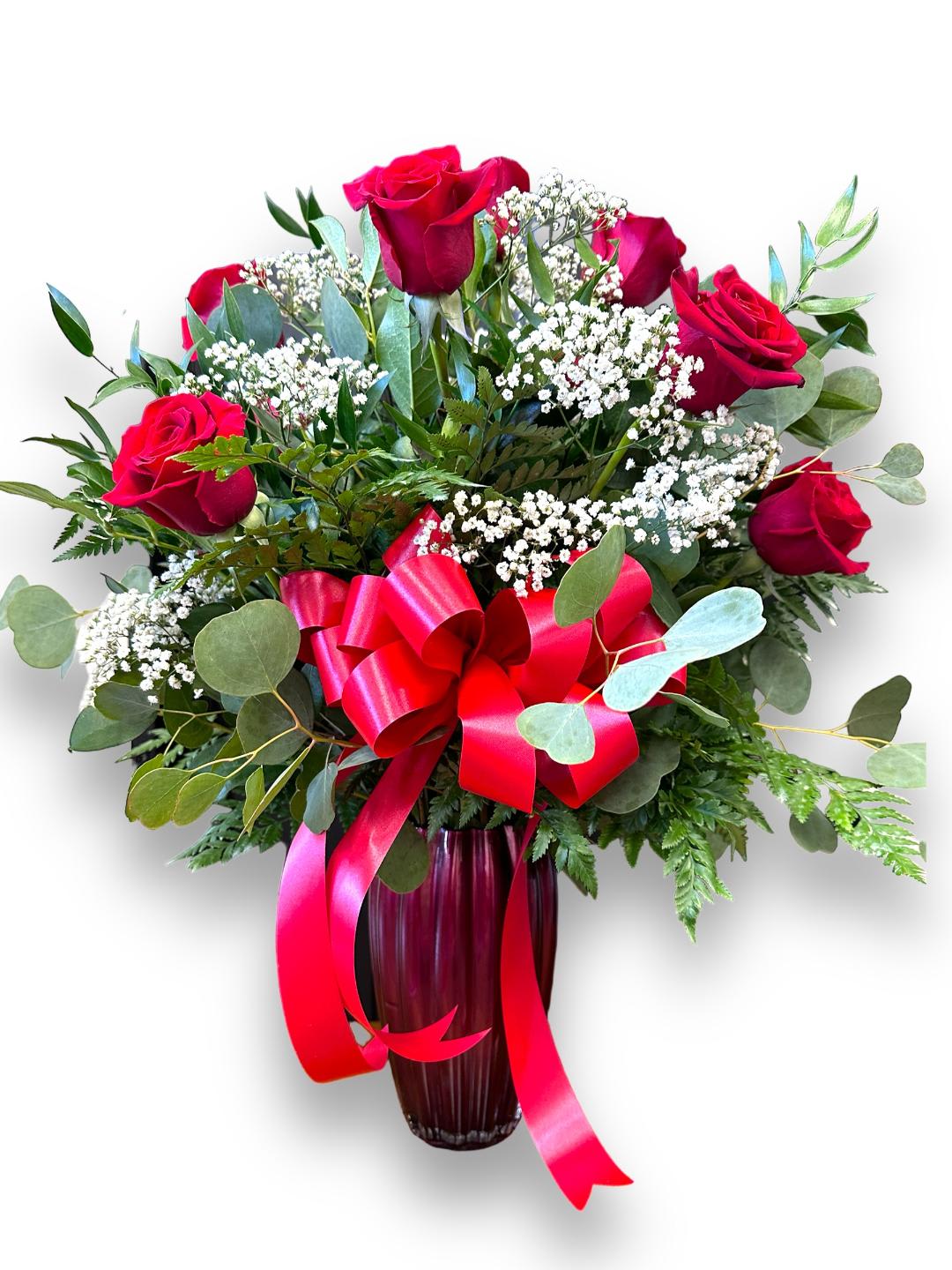 One dozen red roses in a ceramic red vase. - Send this spectacular arrangement of one dozen red "Freedom" roses with babies breath and a variety of assorted greenery in a ceramic scalloped red vase. This is THE Valentines gift that people in the office will be talking about.
