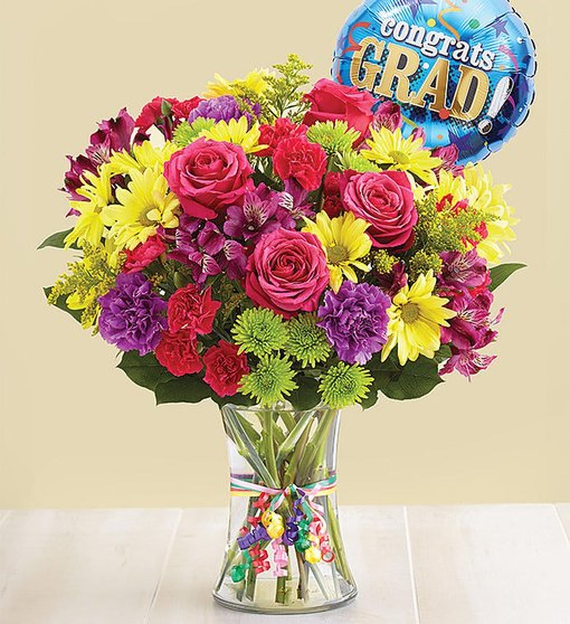 Congrats Grad Bouquet with Balloon - Every graduate deserves a day to celebrate, and we’ve got just the gift. Our hand-designed bouquet is brimming with the best and brightest blooms, gathered inside a charming vase, tied with ribbon. We’ve even included a festive balloon for an extra special way to remember their milestone!  All-around arrangement with hot pink roses and mini carnations, yellow daisy poms, Athos poms, purple Peruvian lilies (alstroemeria) and carnations; accented with assorted greenery  Choice of balloon subject to availability.