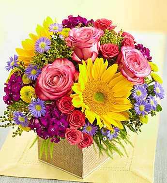 Country Roads Bouquet - Inspired by the fresh, colorful flowers youâd find alongside a winding country road, this charming compact bouquet is hand-arranged with a lively mix of sunflowers, roses and dianthus inside a rustic burlap cube vase. We hope it brings a smile to someone special in your life, whether itâs for a special occasion, or no particular reason at all!