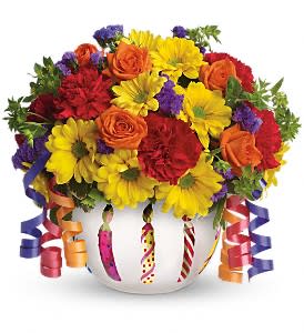 Colorful mixed flower arrangement in a white vase with curling ribbons