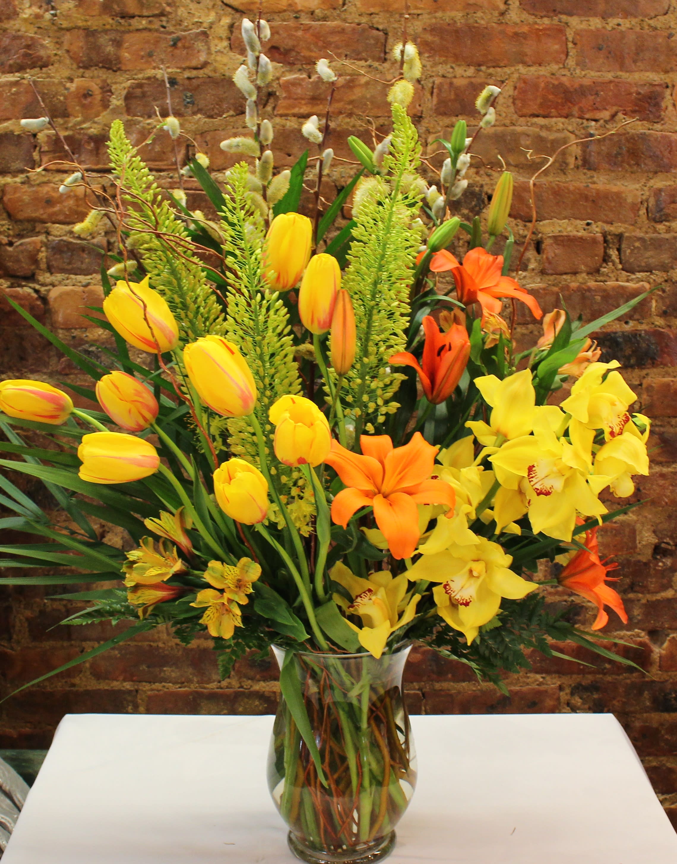 Mixed bouquet of yellow and orange flowers in a clear glass vase