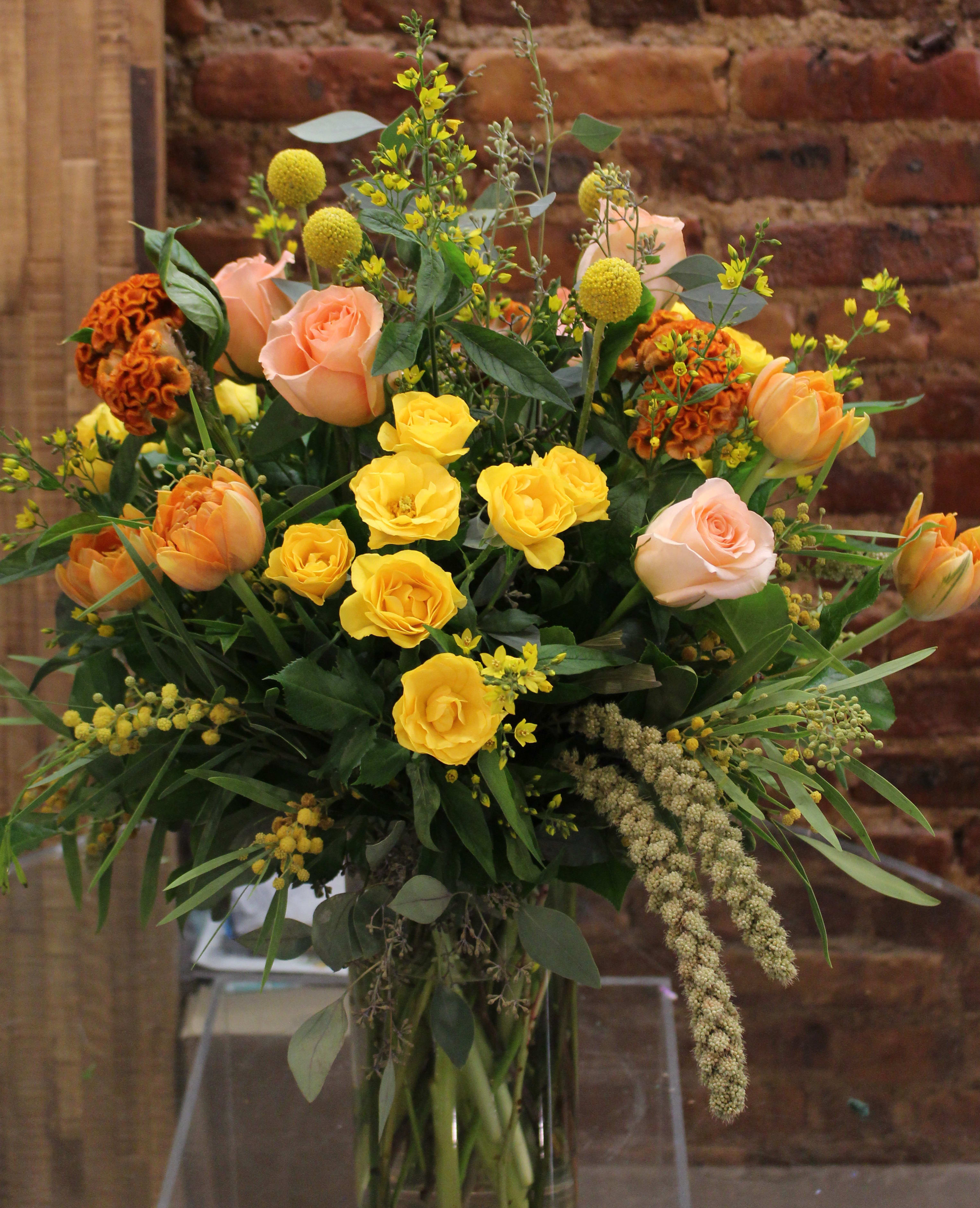 Bouquet of yellow and peach roses in a glass vase