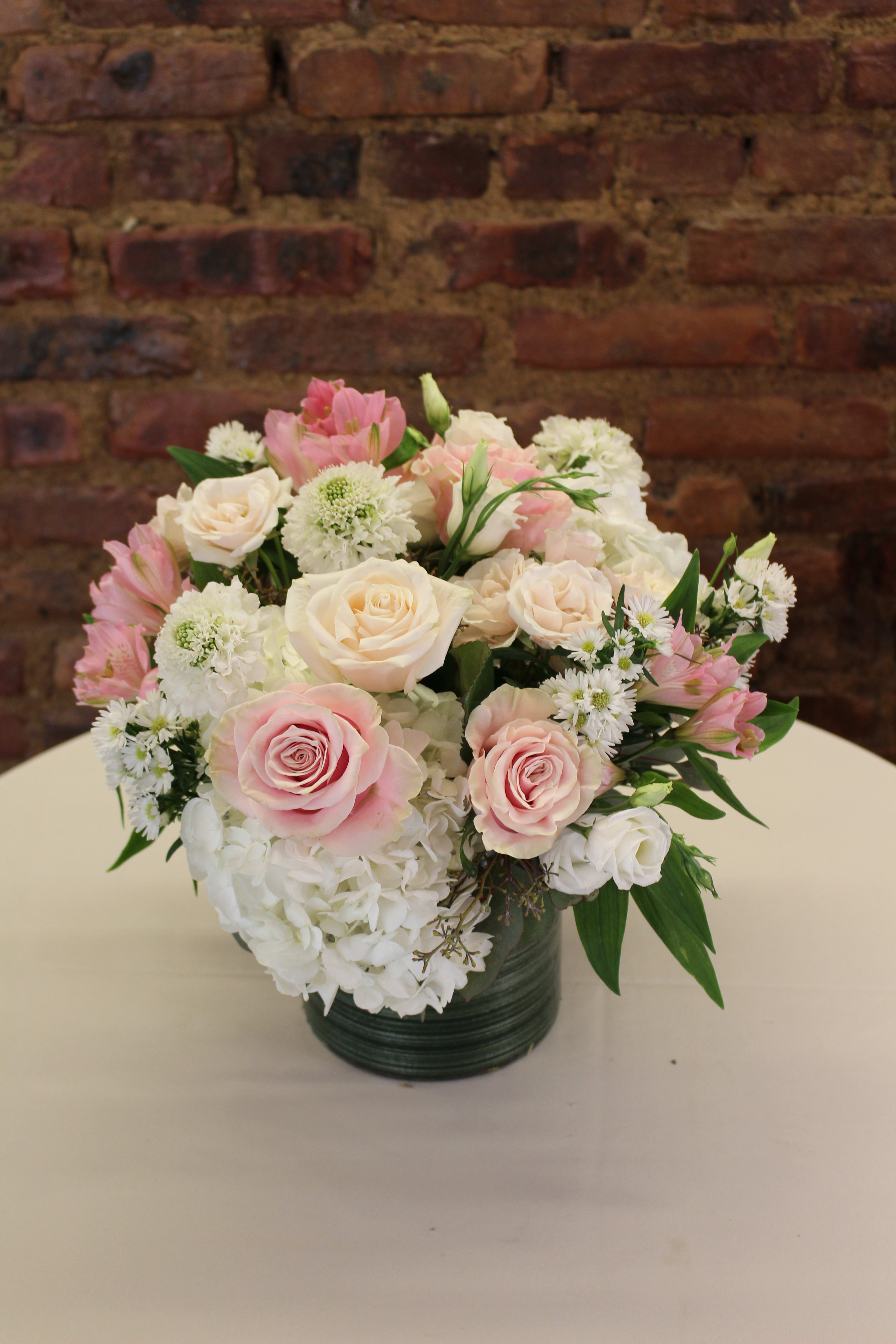 Pink and white roses with hydrangeas in a dark vase