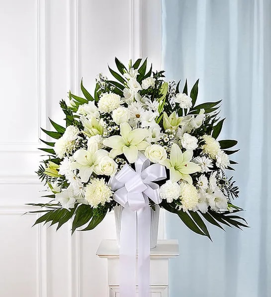 White floral standing arrangement with a ribbon bow in a vase