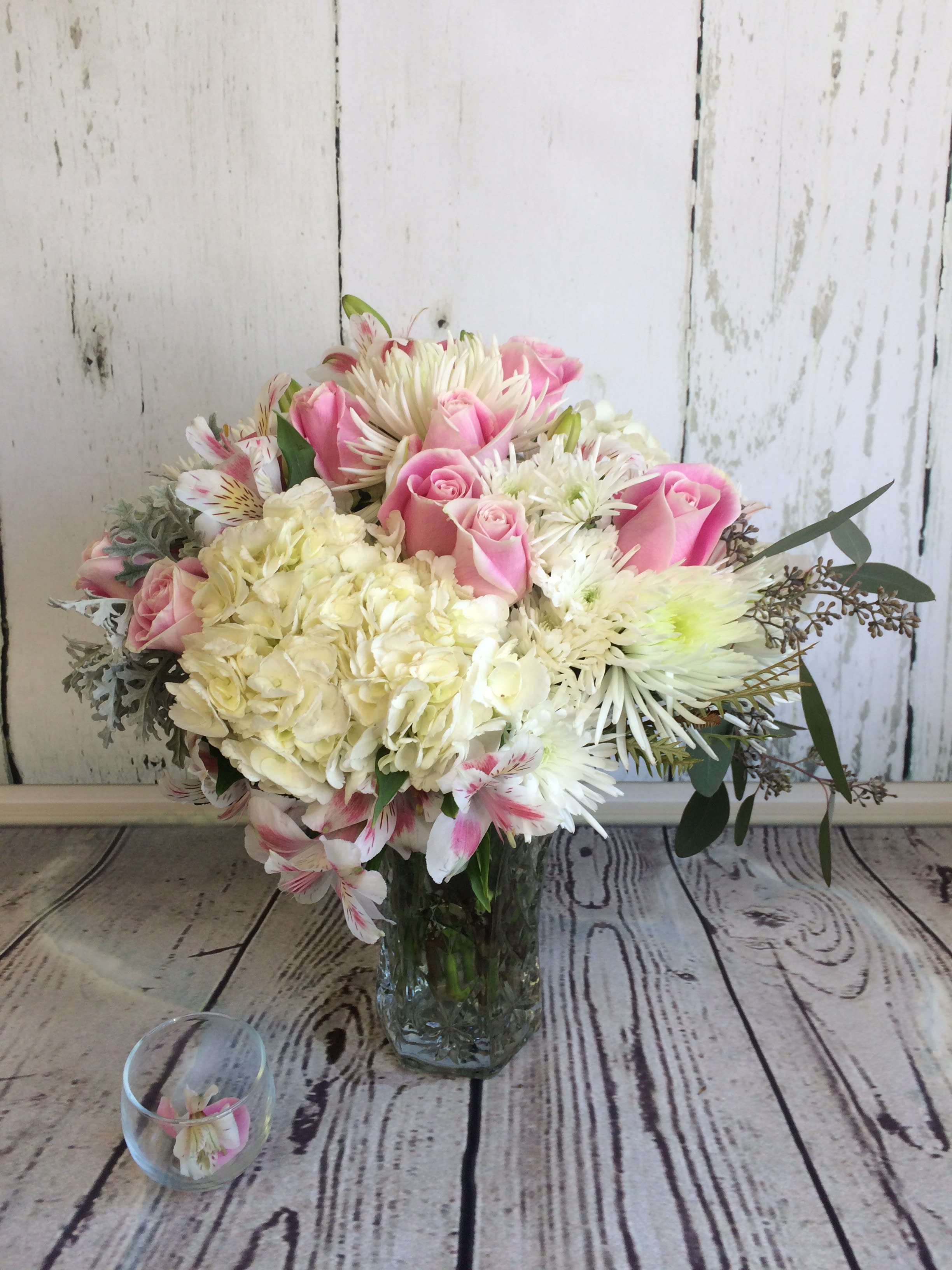 Pink roses and white mixed flowers arranged in a clear glass vase