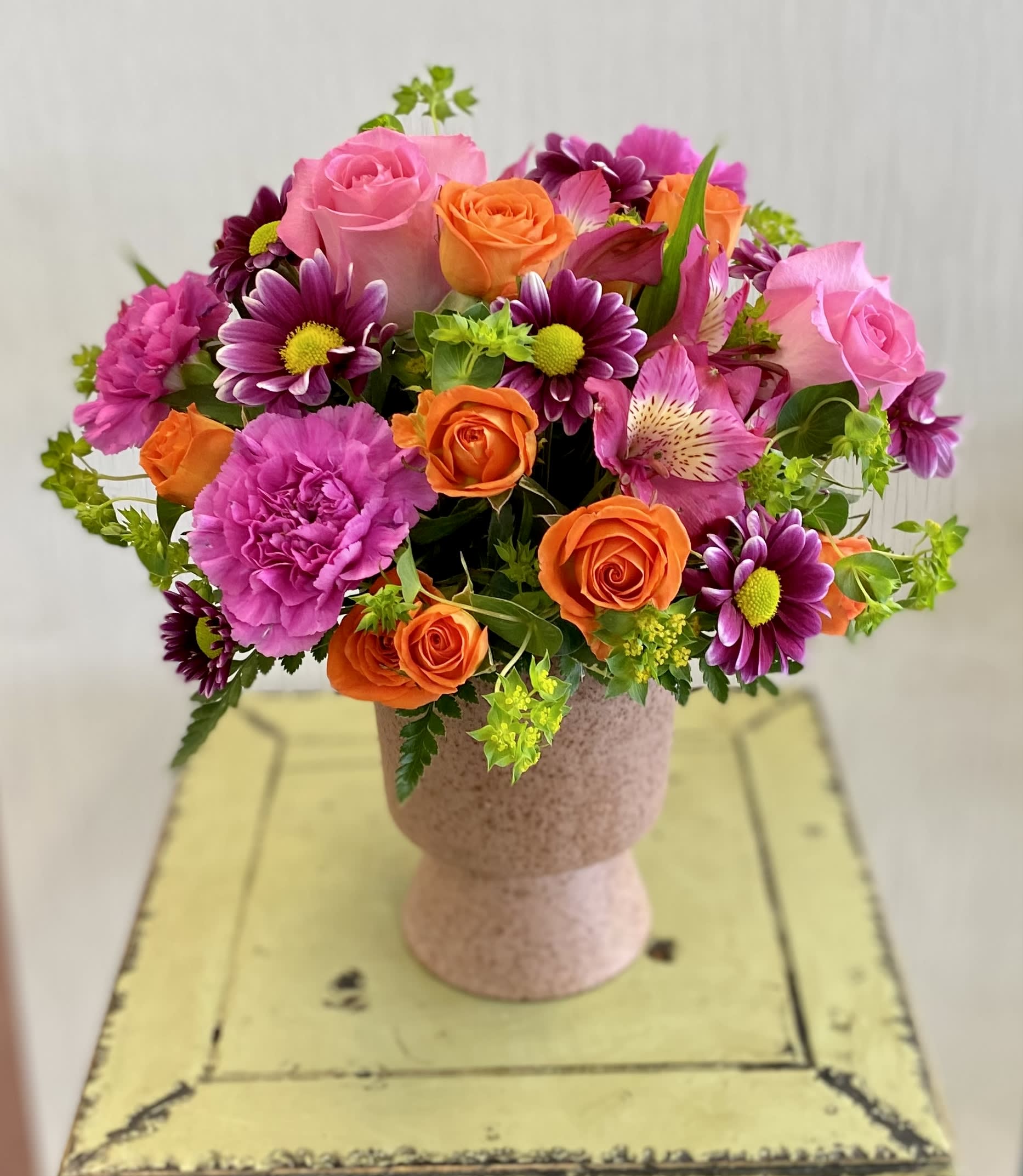 Bouquet of pink, orange, and purple flowers in a pedestal vase
