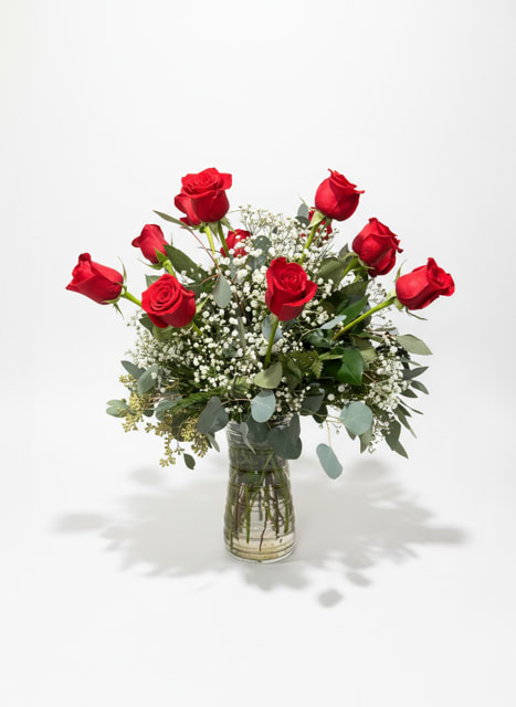 Red roses arranged in a clear glass vase with white filler flowers