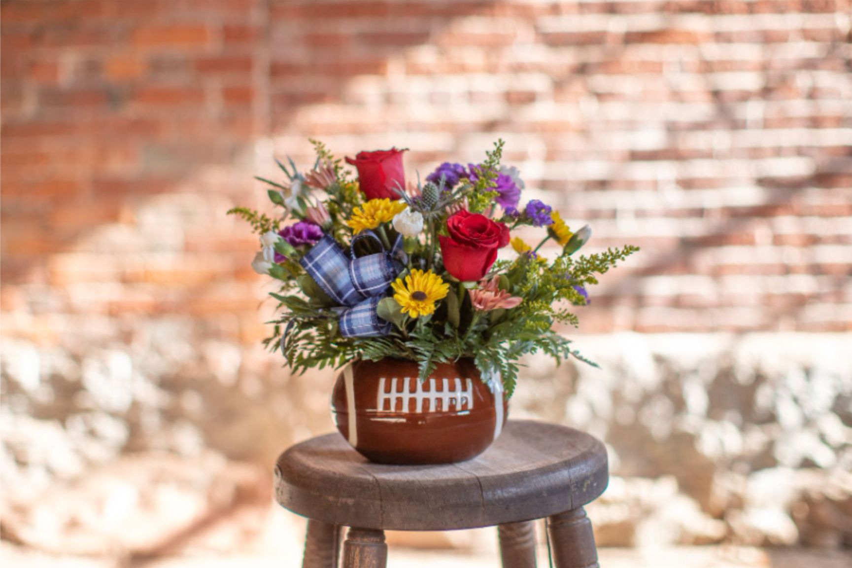 Bouquet of red roses and mixed flowers in a football-shaped vase