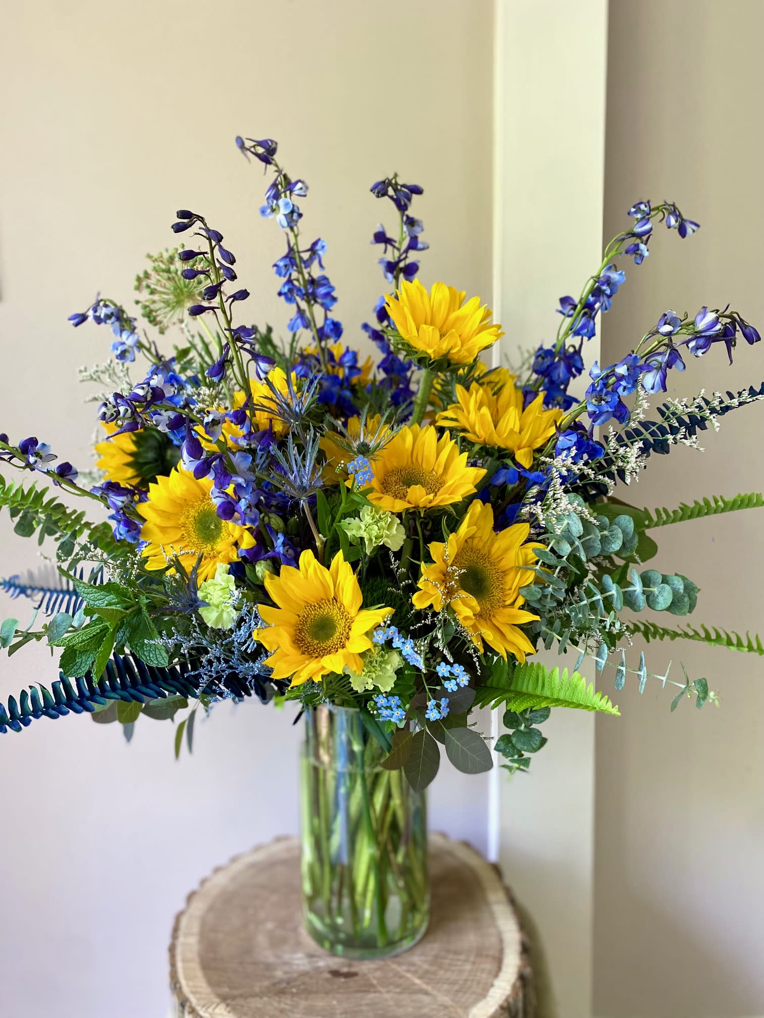Bouquet of yellow sunflowers and blue flowers in a glass vase