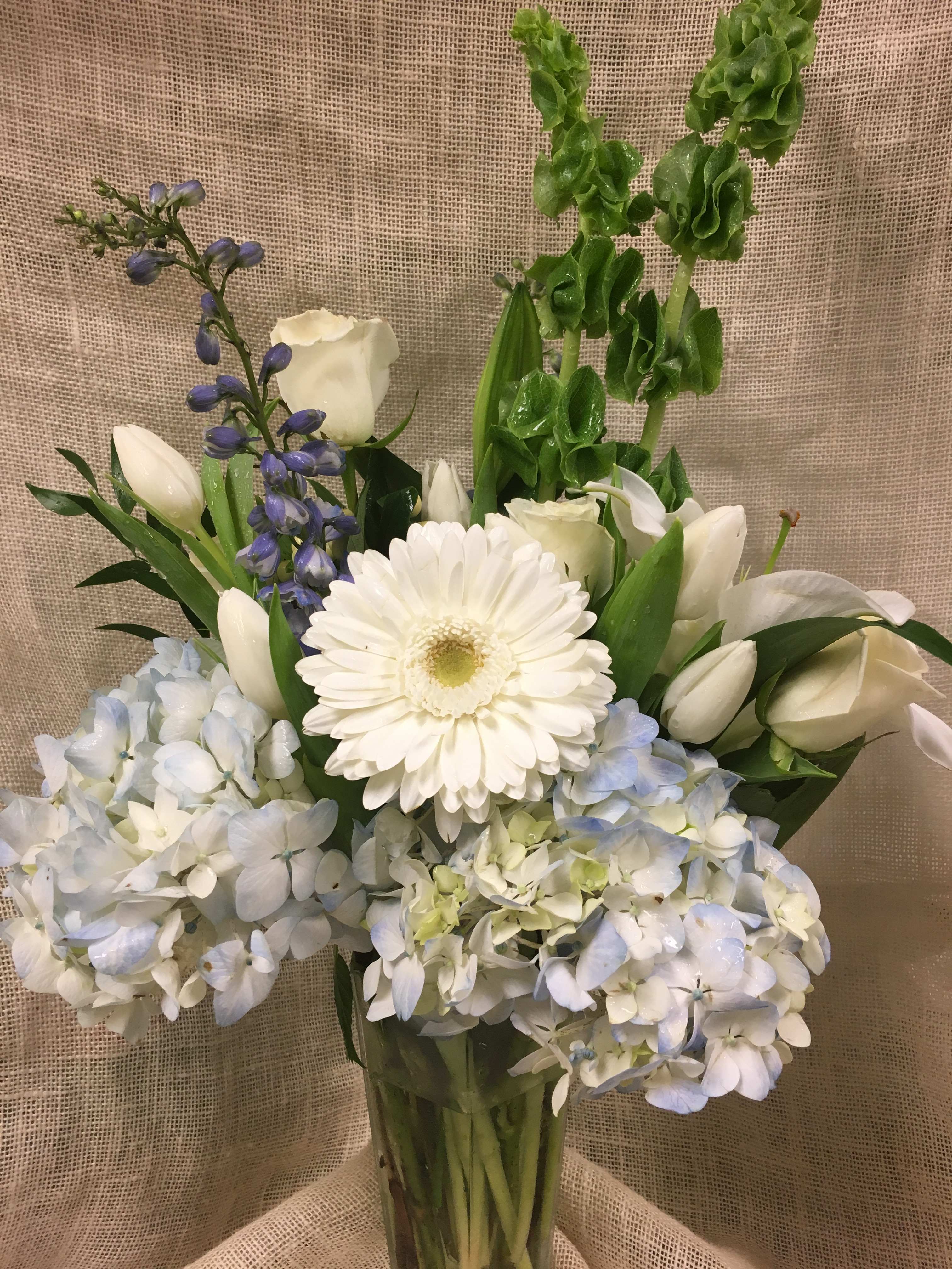 Peacemaker - This soft, beautiful arrangement is the perfect design to convey your deepest sympathy to a grieving family with peaceful colors and shapes.   We custom create each piece- based on availability and seasonality of flowers, and want each arrangement to be one of a kind.  Be assured- your arrangement will have the look and feel you've chosen.  Please feel free to leave comments for the designer you would like us to take into account in designing your unique arrangement.