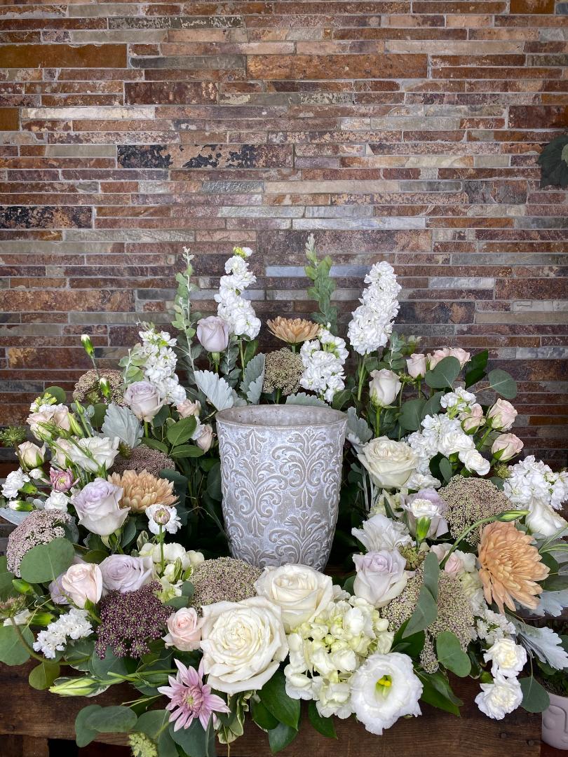 Symmetrical floral arrangement around a decorative urn with white and blush blooms