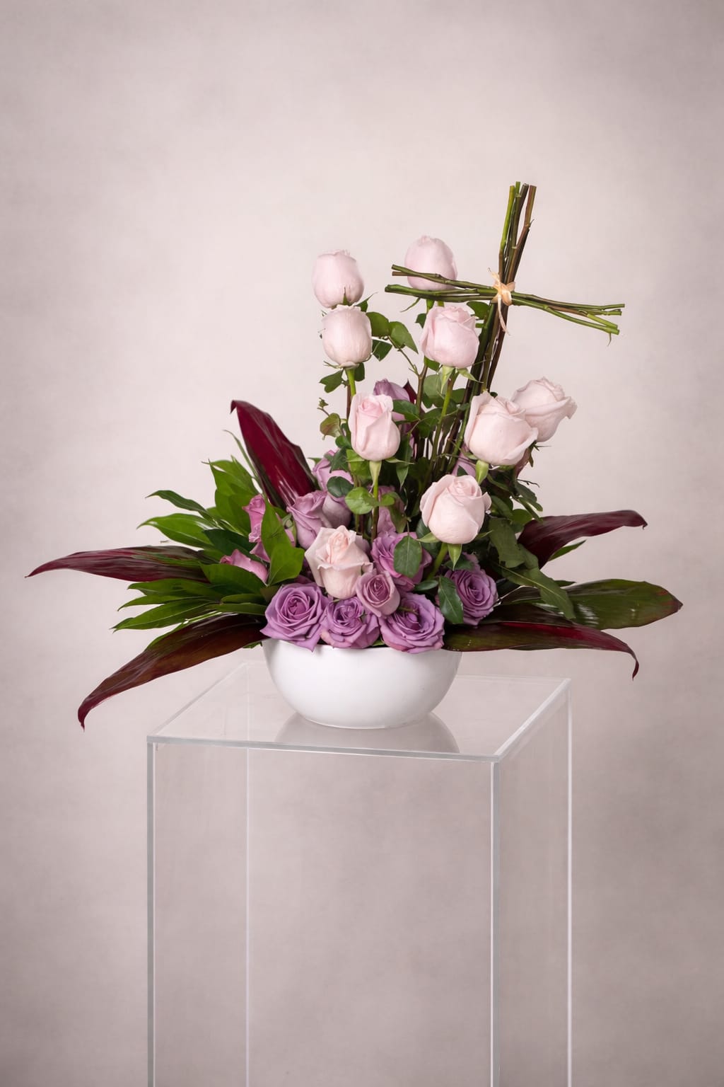 Serenity  - A deeply heartfelt sympathy tribute featuring lush, velvety roses and rich exotic foliage, gracefully accented with a beautifully structured cross. A timeless and elegant expression of love, compassion, and unwavering support — thoughtfully crafted to bring comfort and solace during life's most tender moments.