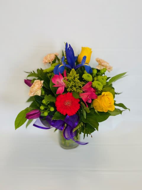 Colorful mixed bouquet in a glass vase with ribbon