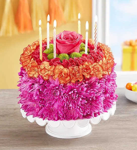 Birthday Wishes Flower Cake Vibrant - EXCLUSIVE If you want their birthday to be the brightest day of the year, your wish has come true! Our vibrant new flower cake has all the ingredients for a happy celebration: hot pink and fiery orange blooms—and candles to top it off. This confection-inspired creation is the perfect centerpiece for their party.