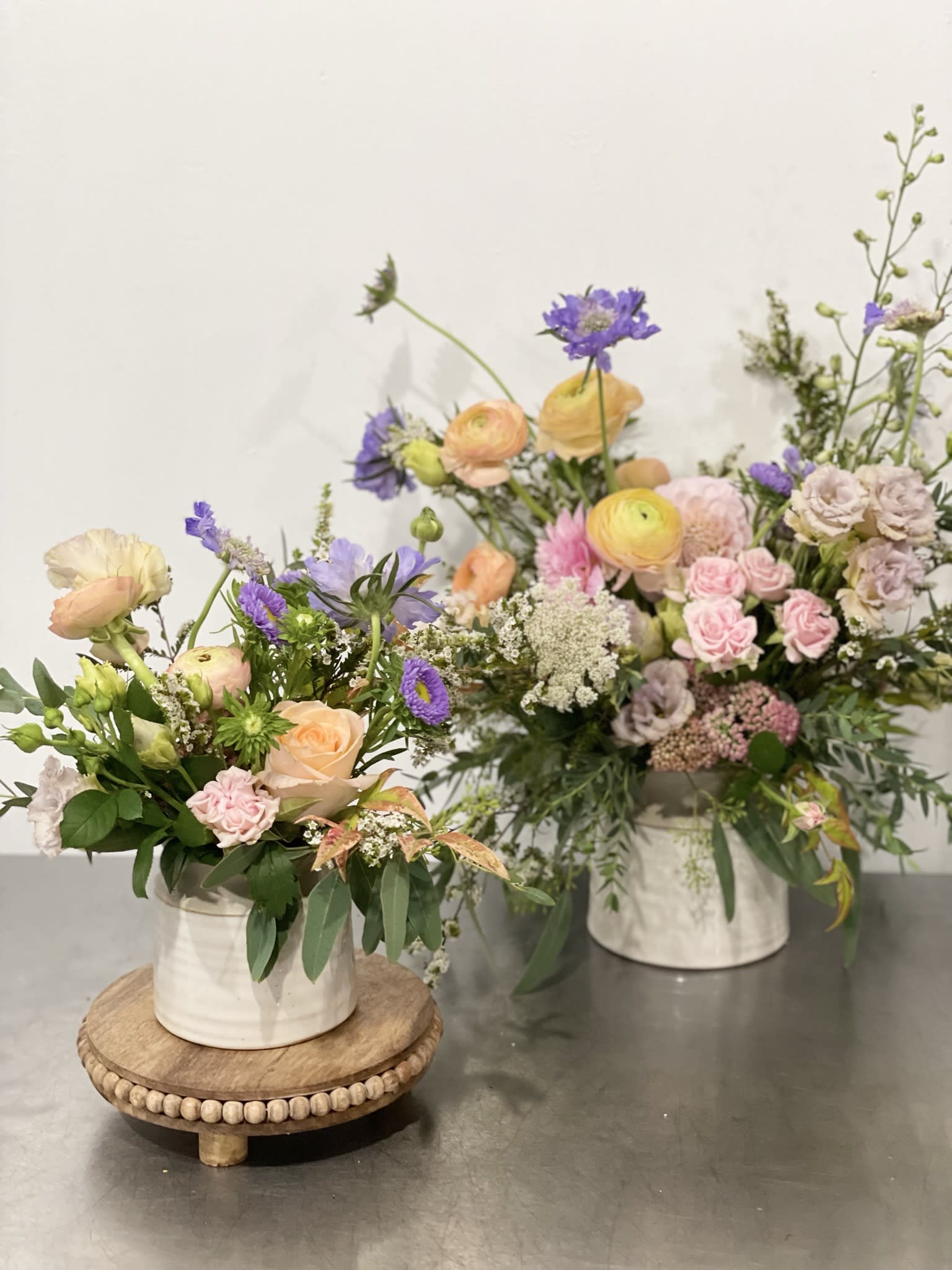 Two pastel floral arrangements in white containers on a table