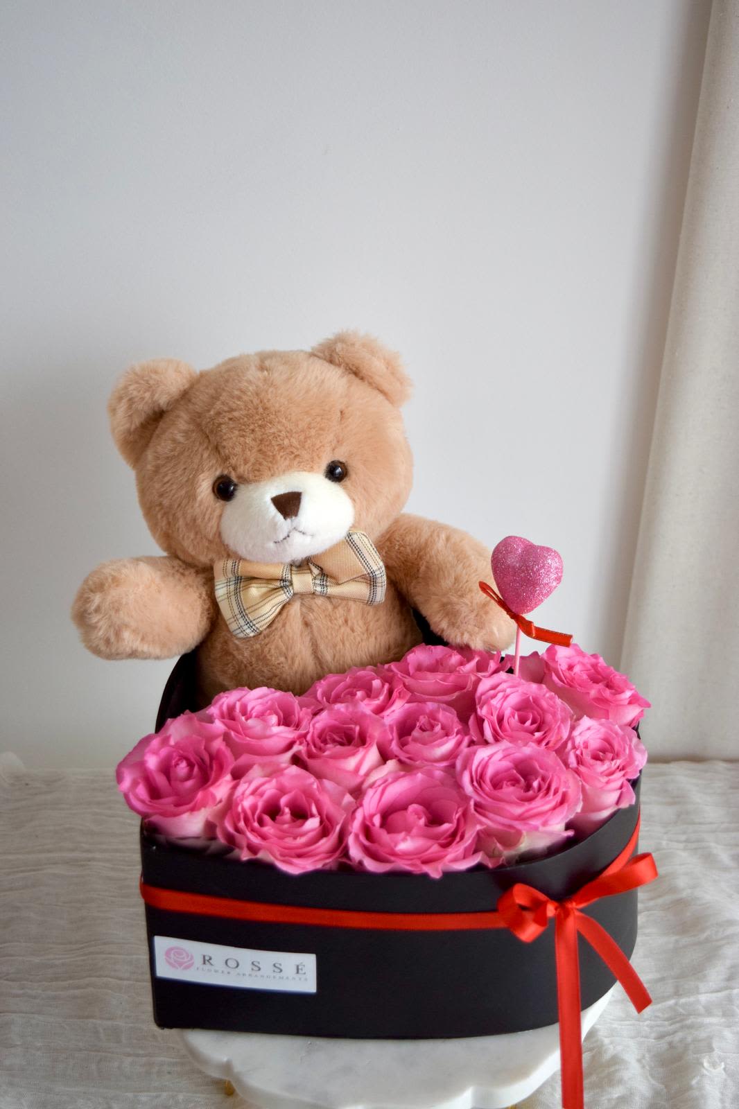 Pink roses in a black box with a teddy bear and heart topper