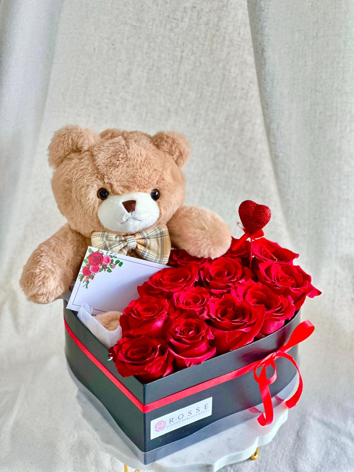 Teddy bear with red roses in a black gift box