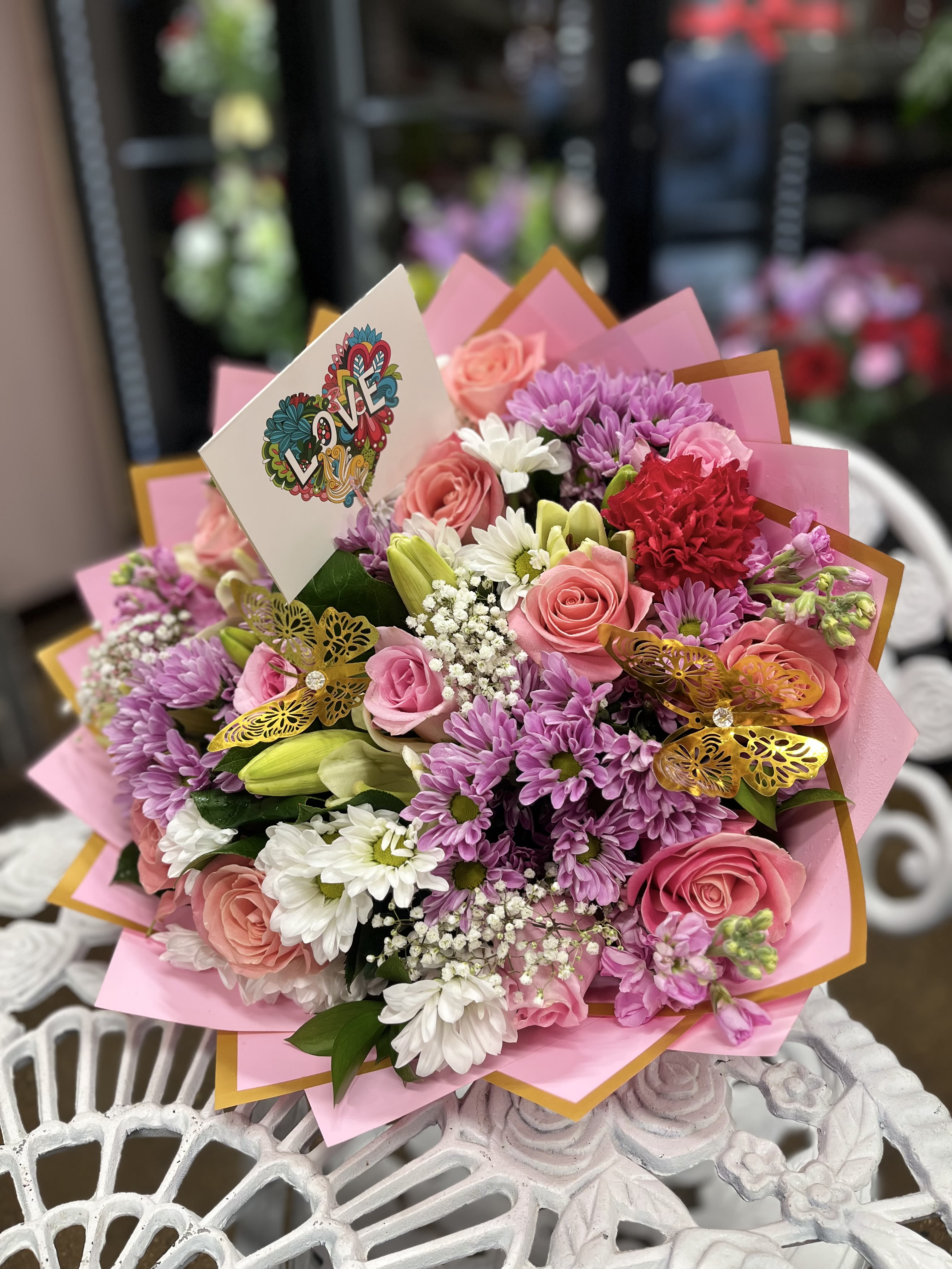 Pink and purple bouquet with roses, daisies, and a LOVE card