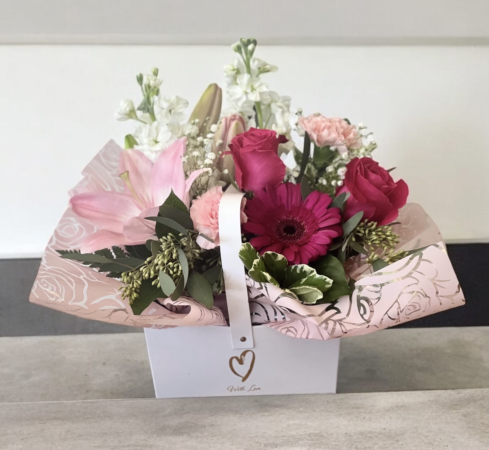 Pink and white mixed flower arrangement in a white gift box
