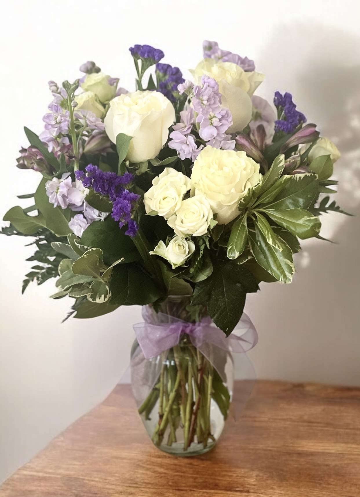 Bouquet of white roses and purple flowers in a glass vase