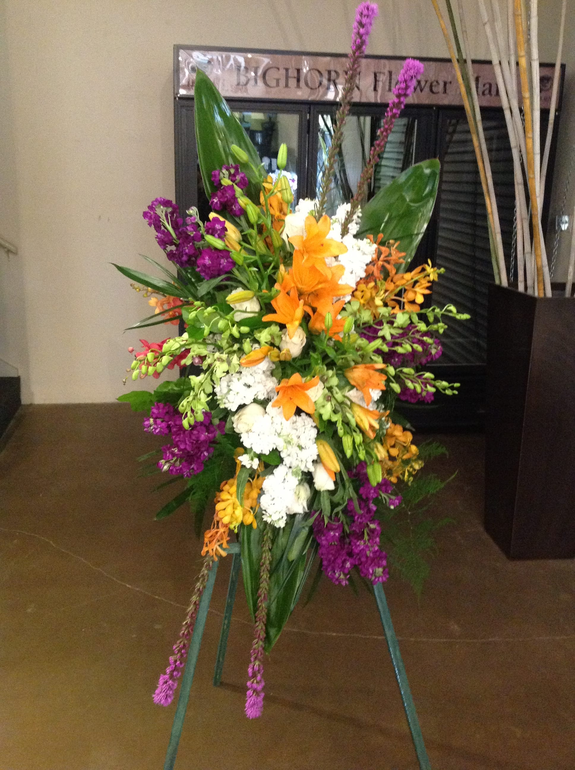 Tall standing floral spray with orange, purple, white, and yellow blooms