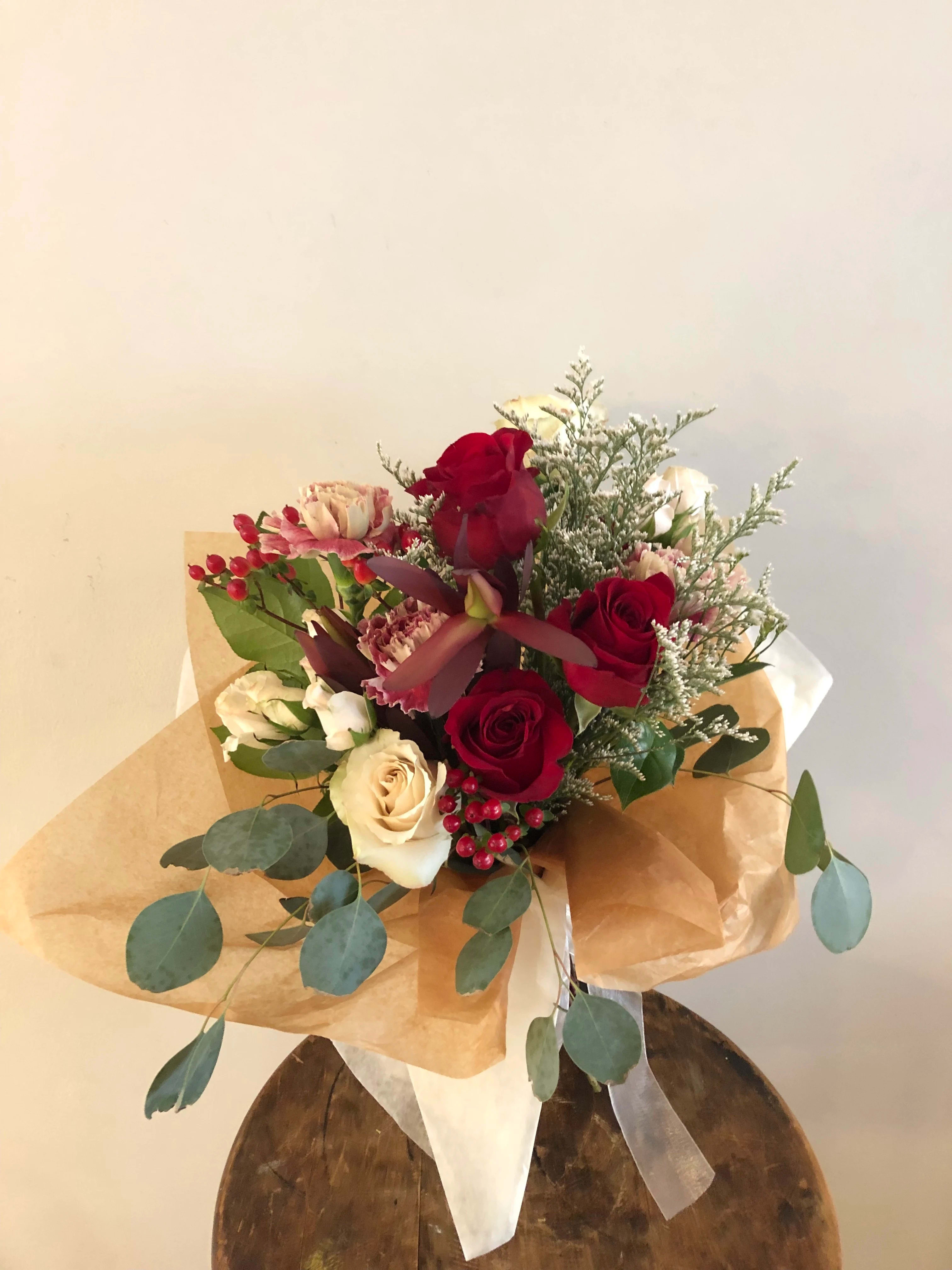 Bouquet of red and cream roses with pink accents wrapped in brown paper