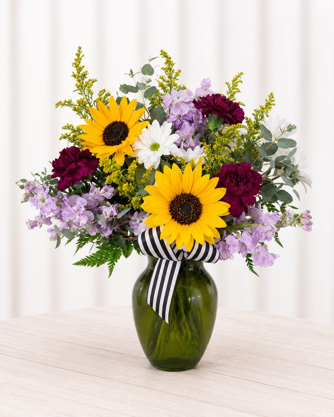 Sun kissed  - Bright yellow sunflowers take center stage in this Sun Kissed flower arrangement, a cheerful flower arrangement perfect for birthdays, thank-you gestures, or "just because" moments when you want someone to feel seen. The mix of summer-ready sunflowers with purple and white accents reads both vibrant and homey, making it equally right for graduations, anniversaries, or a get-well bouquet that lifts spirits.