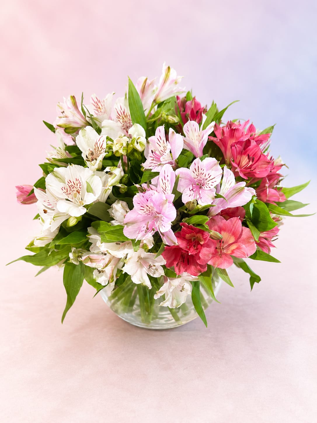 Blushing Petals - Soft, sweet, and effortlessly elegant, Blushing Petals features a lush gathering of pink and white alstroemeria accented with fresh greenery in a clear glass vase. The delicate mix of blush tones and creamy whites creates a light, airy feel that’s perfect for birthdays, baby showers, thank you gifts, or simply brightening someone’s day with timeless floral beauty.